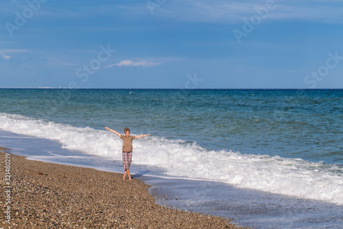 Happy european white kid standing in scenic beach of hotel resort. © Andrii Oleksiienko
