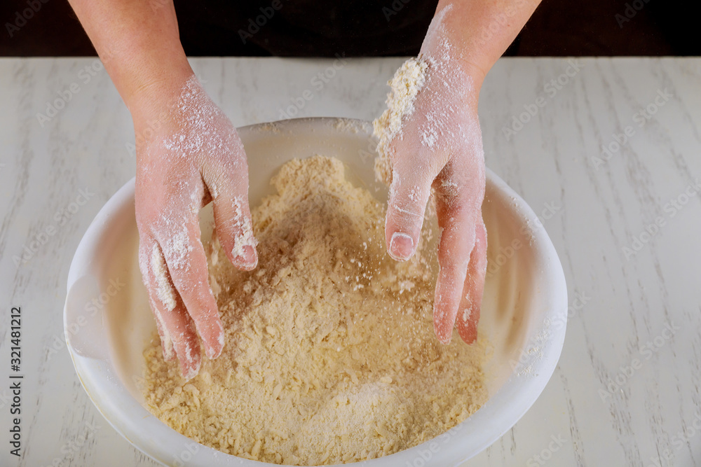 Woman kneading flour, sugar and butter with hands.