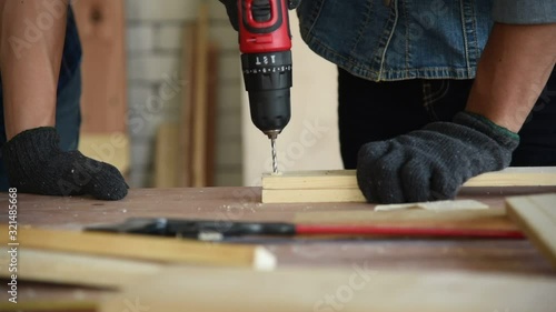 Young Asian group man worker using electric hand drill to build diy wood furniture in workshop
