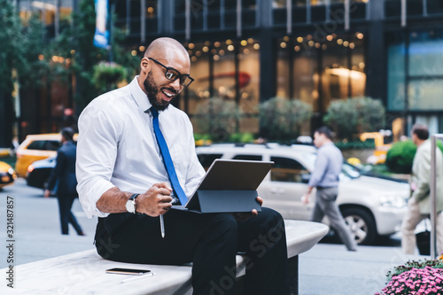 Black successful businessman looking at tablet screen outside