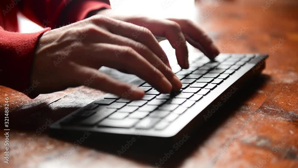 Closeup of caucasian hands typing on black keyword on wooden desk Closeup of caucasian hands typing on black keyword on wooden desk