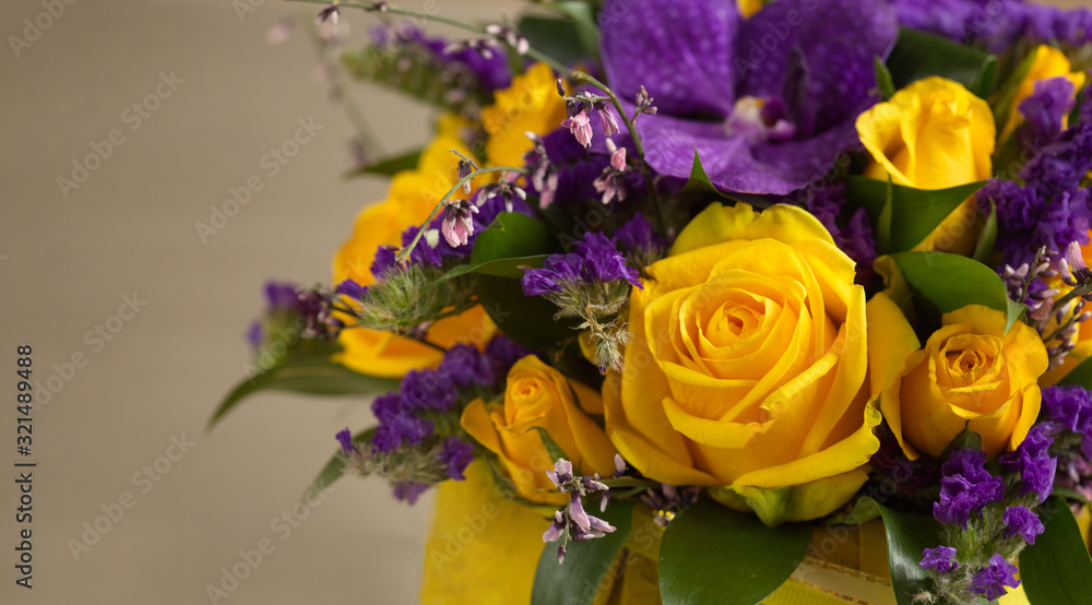 Close-up of a beautiful spring bouquet with yellow roses and purple orchids. Decorative composition of a greeting card for a birthday holiday. Copy space.