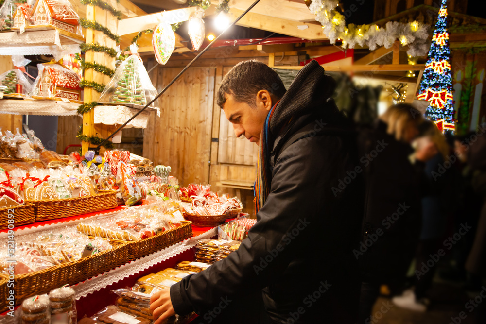 Young guy buying christmas gingerbreads at street market