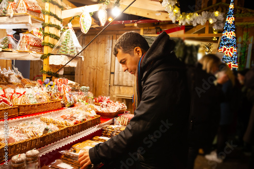 Young guy buying christmas gingerbreads at street market
