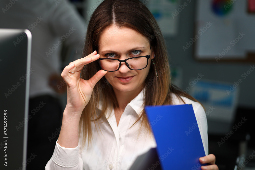 Woman office worker playfully adjusts glasses Woman office worker playfully adjusts glasses