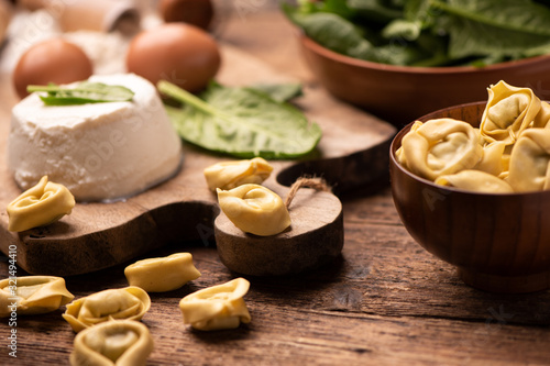 Fesh tortellini ravioli on wooden rustic table with spinach and ricotta