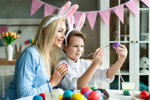 Mother and son wearing in bunny ears together preparing to Easter and painting eggs.- Image