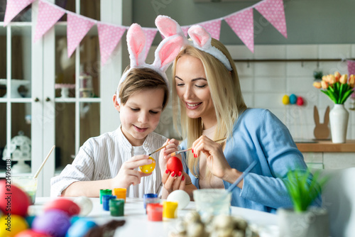 Happy mother and son wearing in bunny ears preparing to Easter and painting eggs. Closeup portrait- Image