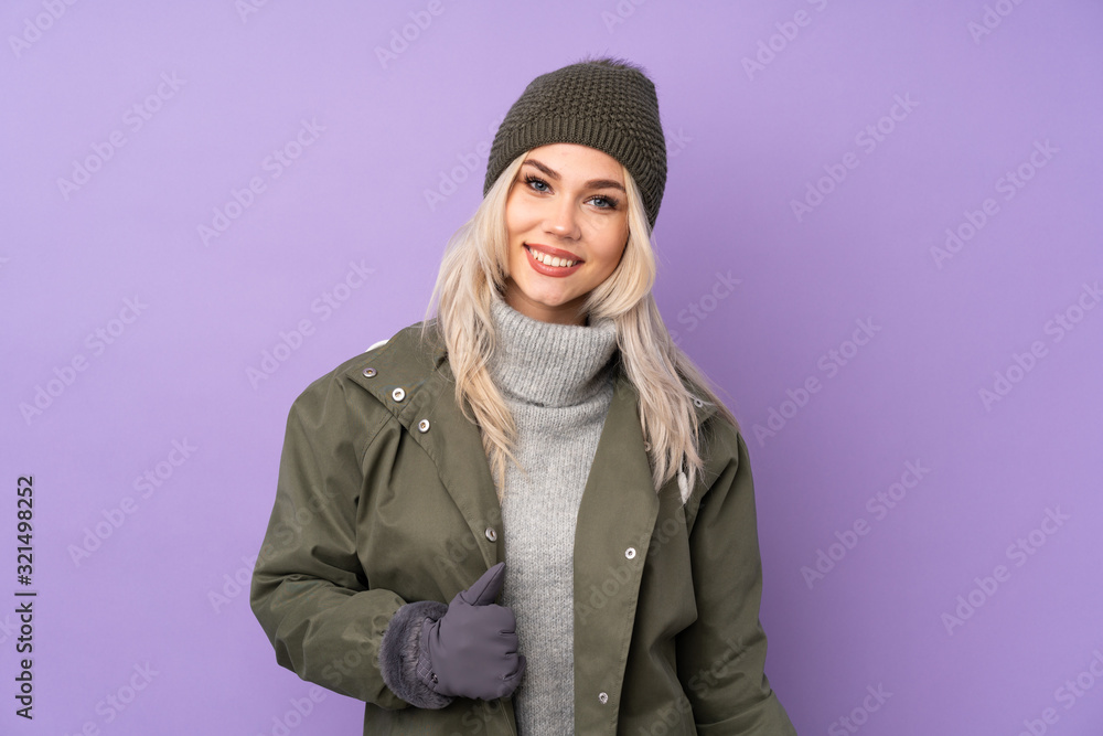 Teenager blonde girl with winter hat over isolated purple background laughing Teenager blonde girl with winter hat over isolated purple background laughing