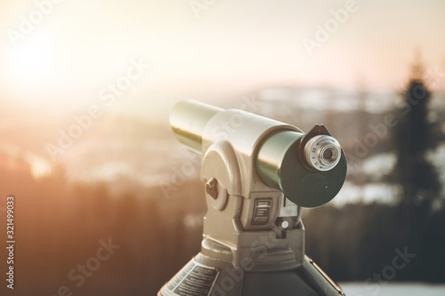 Future and inspiration concept: Tourist binocular, winter landscape and sunshine in blurry background.