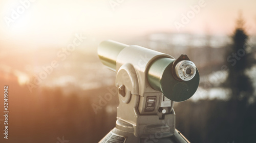 Future and inspiration concept: Tourist binocular, winter landscape and sunshine in blurry background.