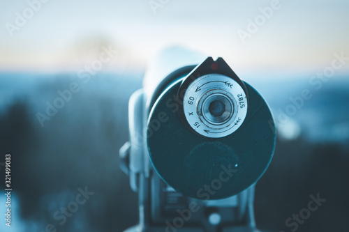 Future and inspiration concept: Tourist binocular, landscape in blurry background. Wintertime