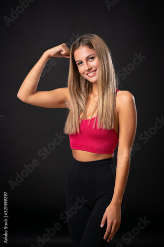 Young sport blonde woman making strong gesture over isolated black background