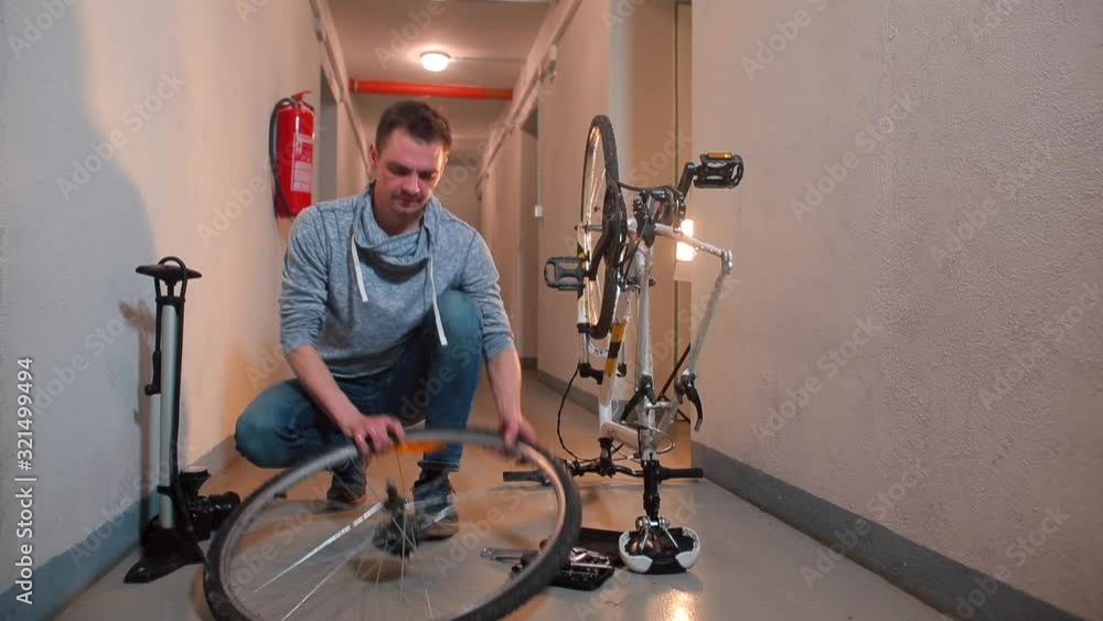 A man rolls up his sleeves and shows a wheel from a bicycle. A man rolls up his sleeves and shows a wheel from a bicycle.