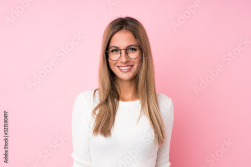 Fototapeta Young blonde woman over isolated pink background with glasses
