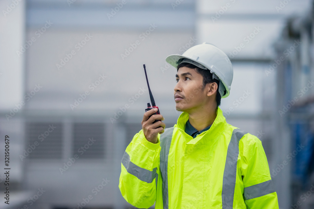 Asian man safety officer in Hard Hats he use radio communication at site work. Asian man safety officer in Hard Hats he use radio communication at site work.