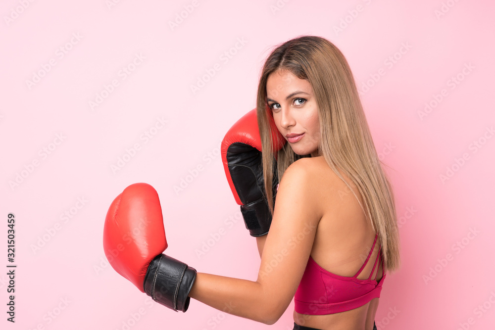 Young sport blonde woman with boxing gloves over isolated pink background