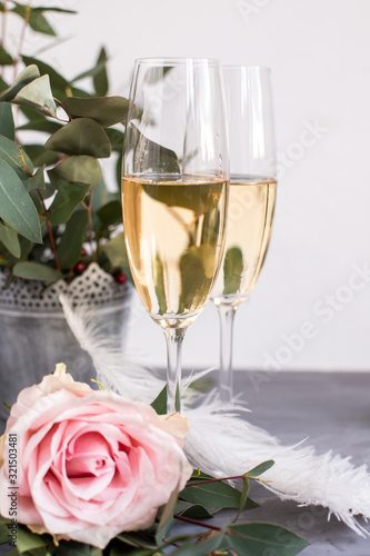 Composition with glasses of vine and flowers on grey concrete background.