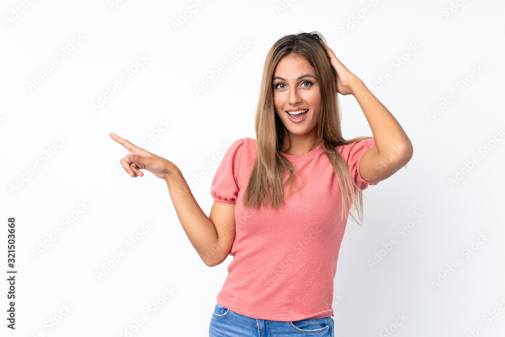 Young blonde woman over isolated white background surprised and pointing finger to the side Young blonde woman over isolated white background surprised and pointing finger to the side