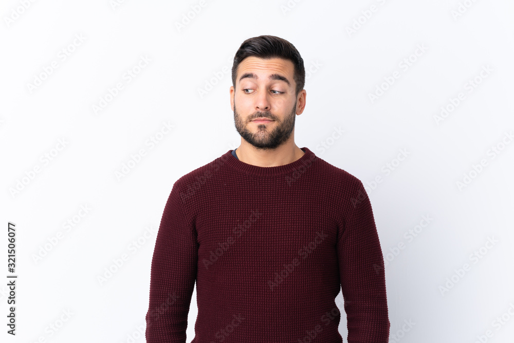 Fototapeta premium Young handsome man with beard over isolated white background making doubts gesture looking side
