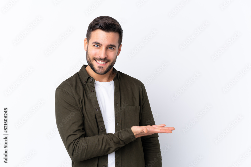 Young handsome man with beard over isolated white background presenting an idea while looking smiling towards Young handsome man with beard over isolated white background presenting an idea while looking smiling towards