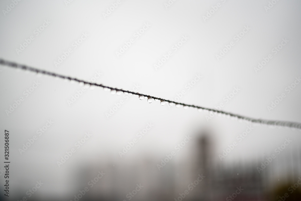 Clothesline wire full of small drops on a rainy day with a selective focus in the center very shallow depth of field