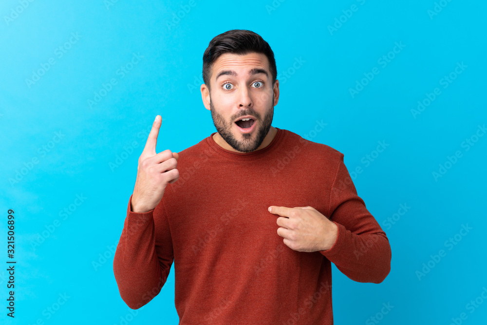 Young handsome man with beard over isolated blue background with surprise facial expression Young handsome man with beard over isolated blue background with surprise facial expression