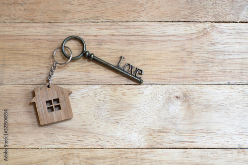 House key in heart shape with home keyring on white wood background