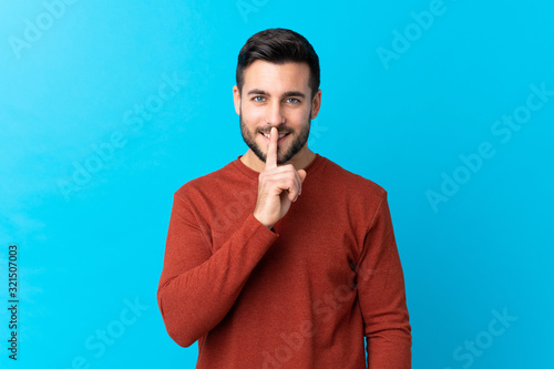 Young handsome man with beard over isolated blue background doing silence gesture