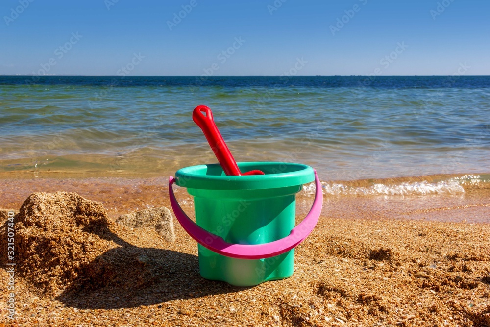 plastic children's toy bucket with a scoop on the sandy shore of the sea beach on a Sunny summer day plastic children's toy bucket with a scoop on the sandy shore of the sea beach on a Sunny summer day
