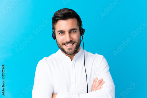 Obraz na płótnie Telemarketer man working with a headset over isolated blue background laughing