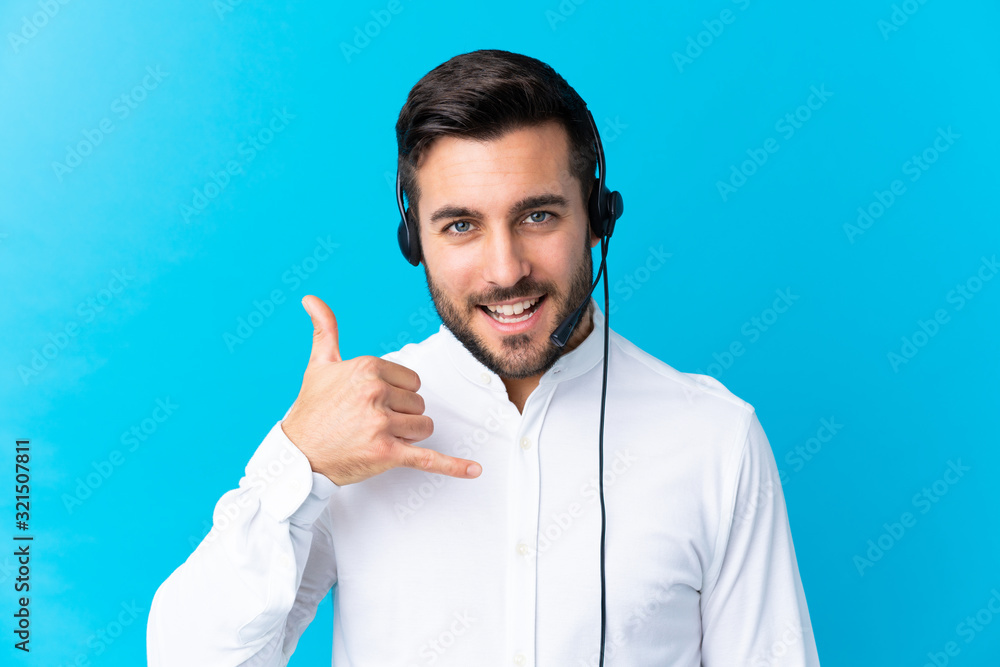 Telemarketer man working with a headset over isolated blue background making phone gesture - obrazy, fototapety, plakaty 