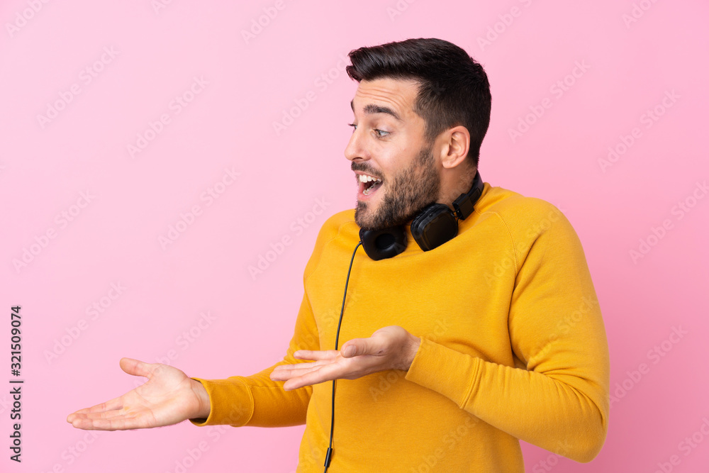 Young handsome man with earphones over isolated pink background with surprise facial expression Young handsome man with earphones over isolated pink background with surprise facial expression