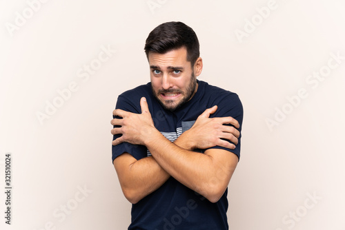 Young handsome man with beard over isolated background freezing
