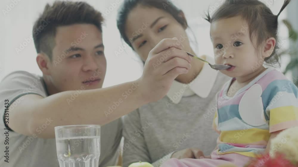 Asian parents Feeding the little daughter's lunch At the dining table in his own house Happily. Family happy moments. Asian parents Feeding the little daughter's lunch At the dining table in his own house Happily. Family happy moments.