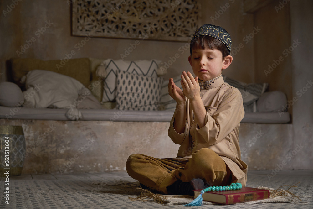 Foto de Small muslim boy in prayer cap and arabic clothes with rosary
