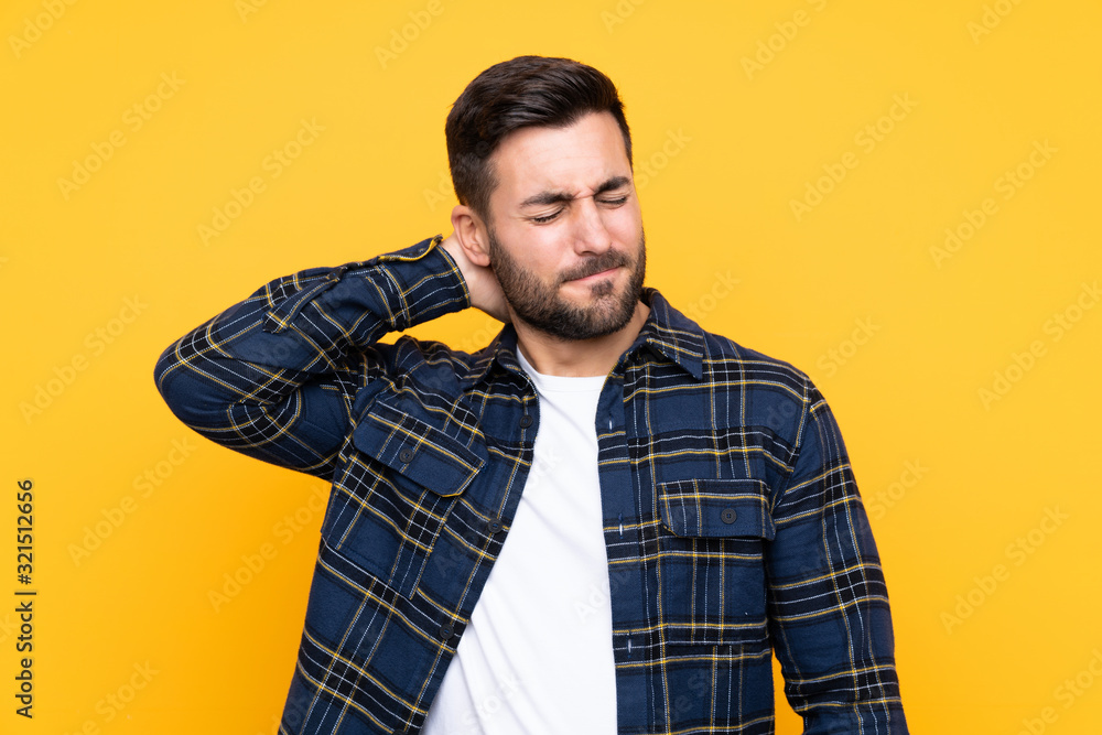 Young handsome man with beard over isolated yellow background with neckache Young handsome man with beard over isolated yellow background with neckache