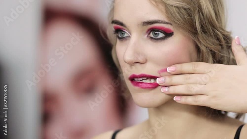 Fashion madness. Beauty art. Woman with night makeup smearing burgundy lip gloss with fingers.