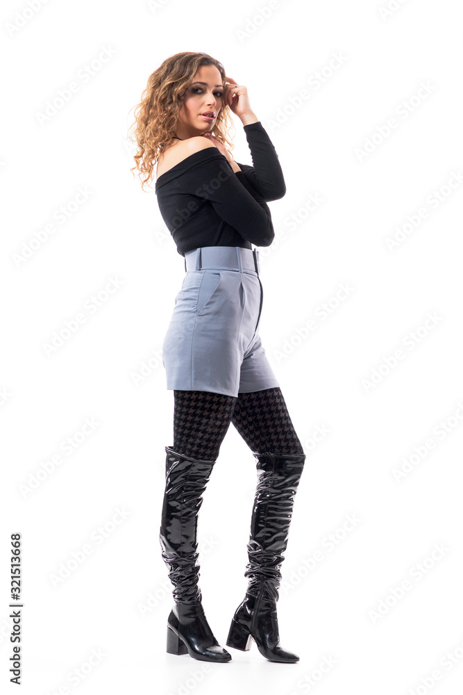 Side view of sexy confident fashionable young woman in knee high black leather boots posing. Full body length isolated on white background. Side view of sexy confident fashionable young woman in knee high black leather boots posing. Full body length isolated on white background.