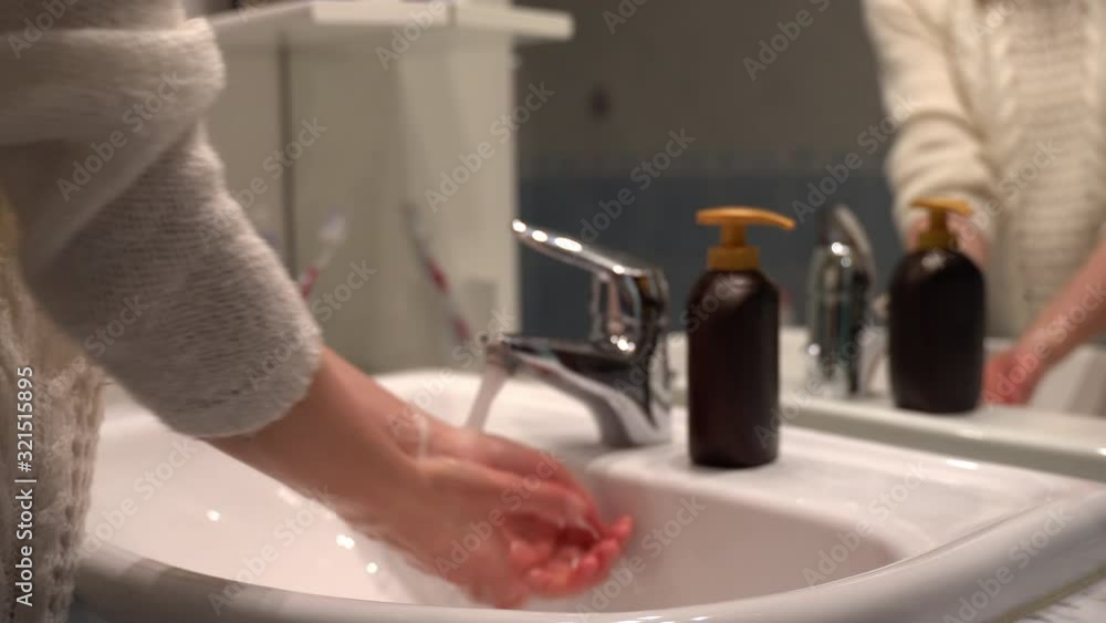 Woman washing hands with soft liquid soap under the water tap. Soap creating foam, hygiene and wellness. Protecting hands from bacteria, everyday body care Woman washing hands with soft liquid soap under the water tap. Soap creating foam, hygiene and wellness. Protecting hands from bacteria, everyday body care