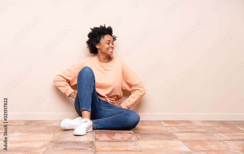 African american woman sitting on the floor posing with arms at hip and smiling African american woman sitting on the floor posing with arms at hip and smiling