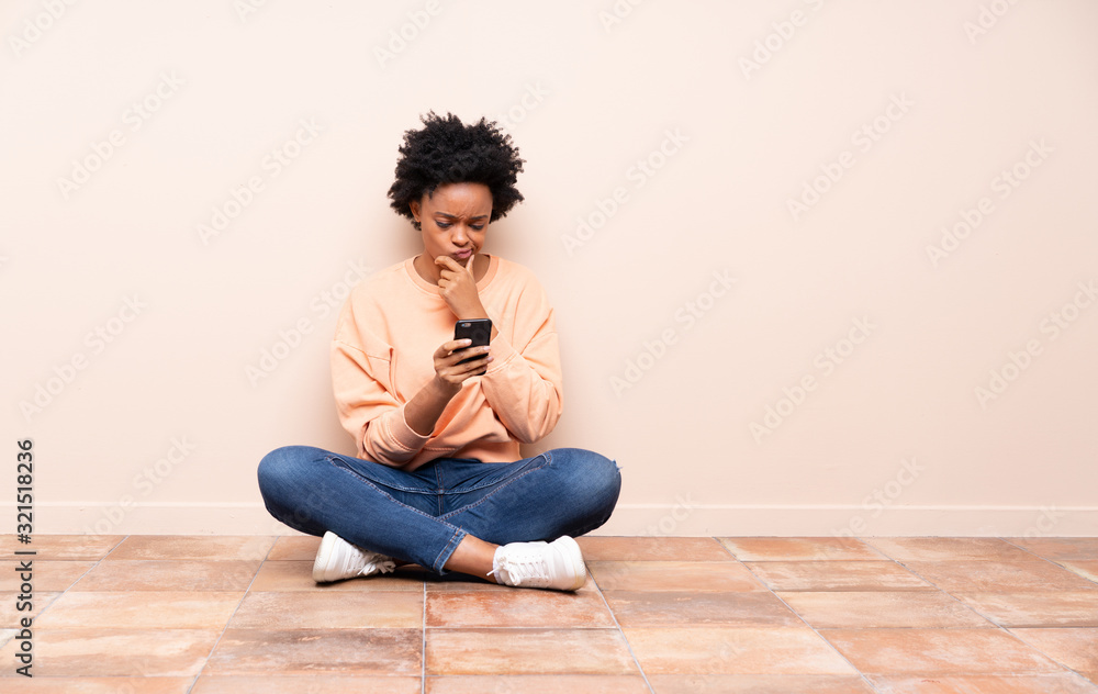 African american woman sitting on the floor thinking and sending a message African american woman sitting on the floor thinking and sending a message