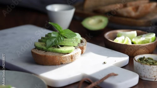 Hands decorate an avocado toast with fresh basil. Healthy eating concept photo