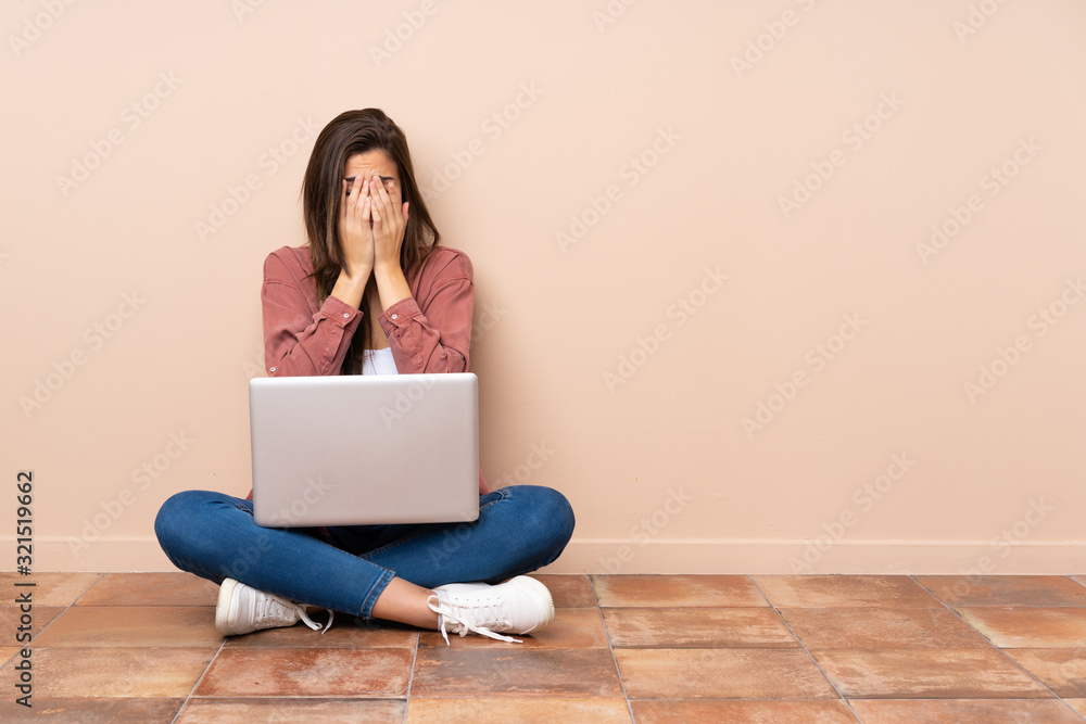 Teenager student girl sitting on the floor with a laptop with tired and sick expression Teenager student girl sitting on the floor with a laptop with tired and sick expression