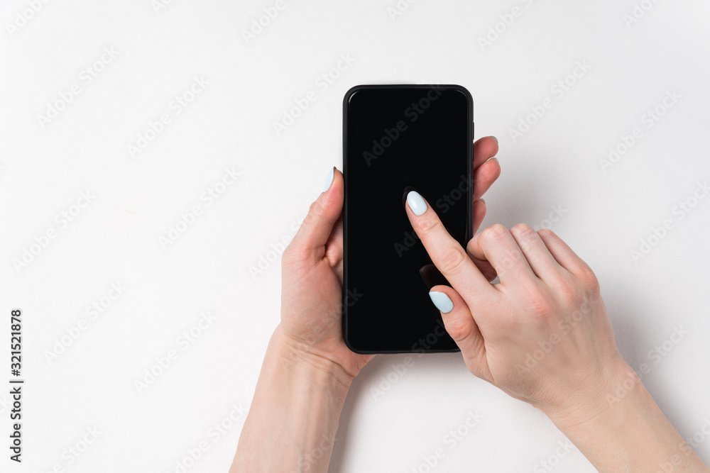 Female hands holding phone and showing on screen. Black display, white background, copy space Female hands holding phone and showing on screen. Black display, white background, copy space