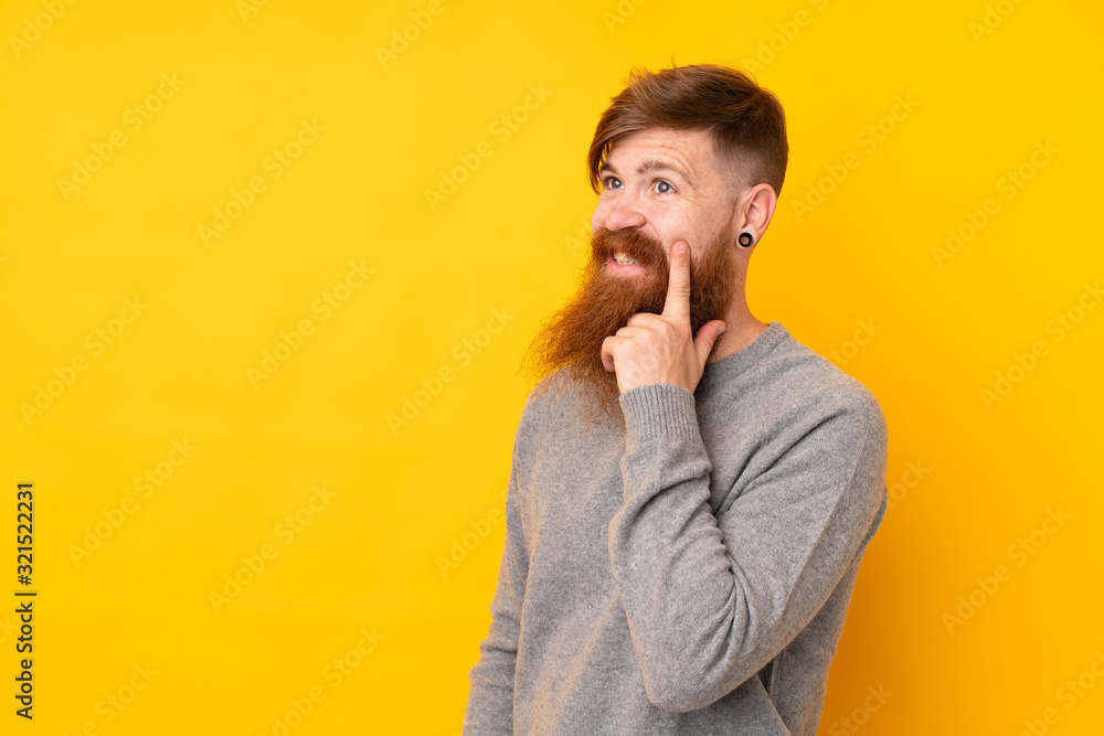 Redhead man with long beard over isolated yellow background thinking an idea while looking up Redhead man with long beard over isolated yellow background thinking an idea while looking up