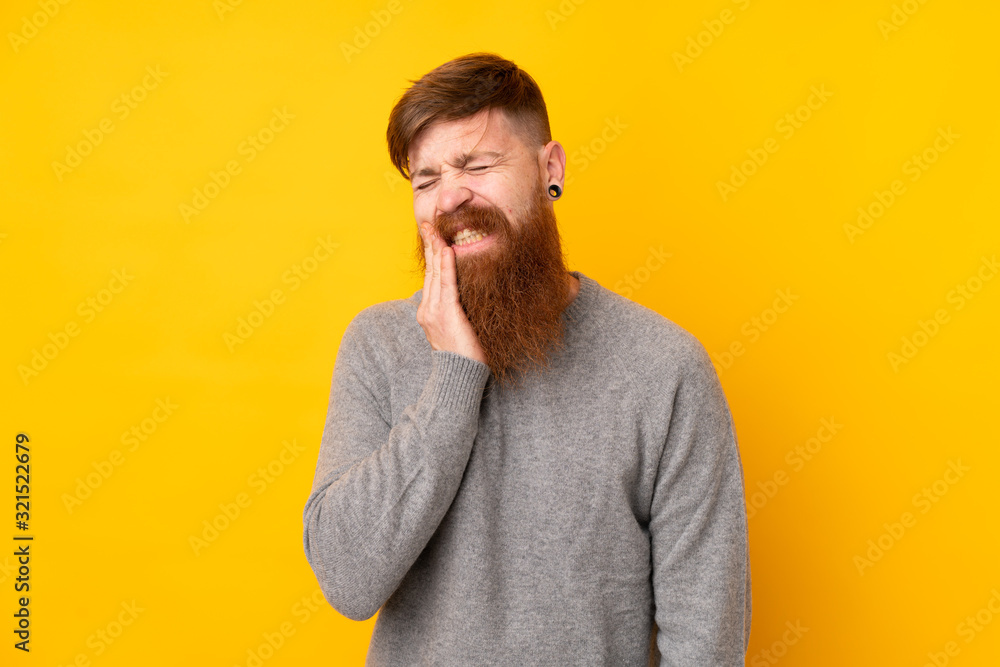Redhead man with long beard over isolated yellow background with toothache Redhead man with long beard over isolated yellow background with toothache