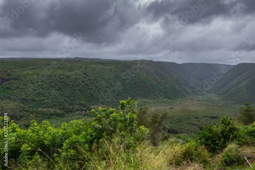 Kohala, Hawaii, USA. - January 15, 2020: Green Pololu valley from start to end under dark rainy cloudscape.  photo