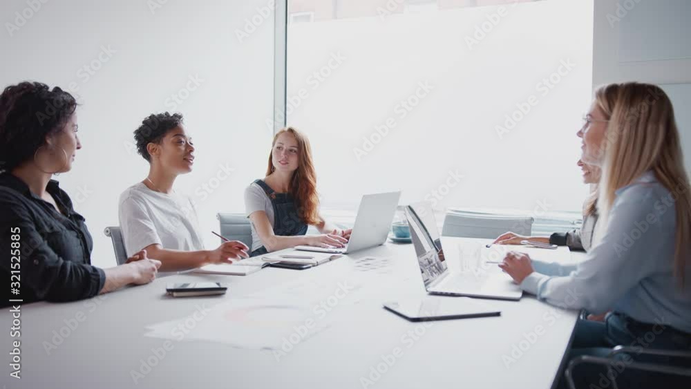 Team Of Young Businesswomen With Laptops And Tablets Meeting Around Table In Modern Workspace Team Of Young Businesswomen With Laptops And Tablets Meeting Around Table In Modern Workspace