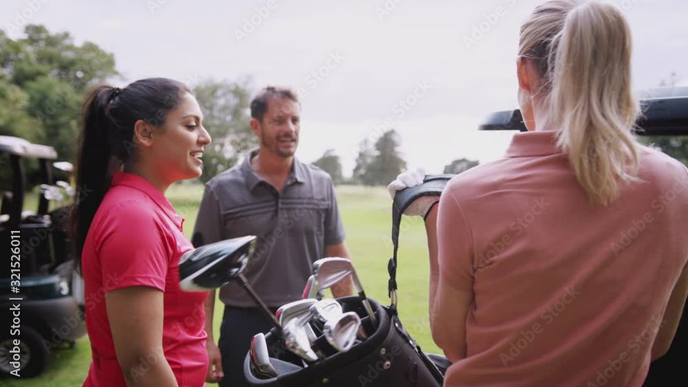 Group Of Male And Female Golfers Standing By Golf Buggy On Course And Choosing Clubs Group Of Male And Female Golfers Standing By Golf Buggy On Course And Choosing Clubs